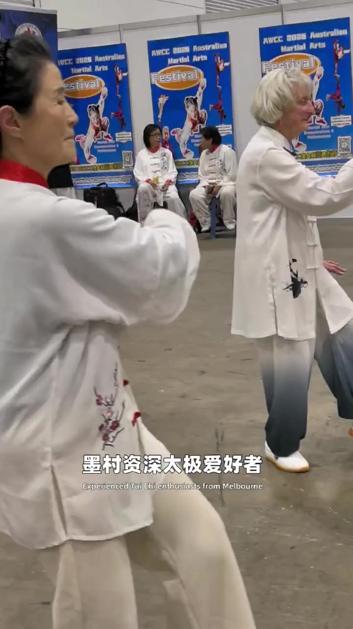 墨爾本會議展覽中心澳中博覽會上，身穿白色練功服的墨爾本太極愛好者在 AWCC 2026澳大利亞武術節橫幅前表演